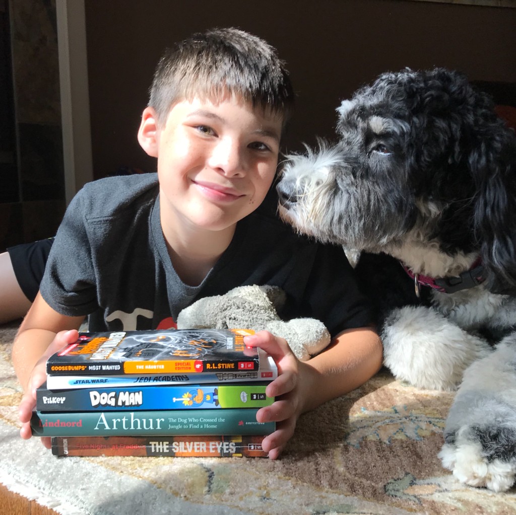 Benjamin with his dog, lying on a rug with a stack of books